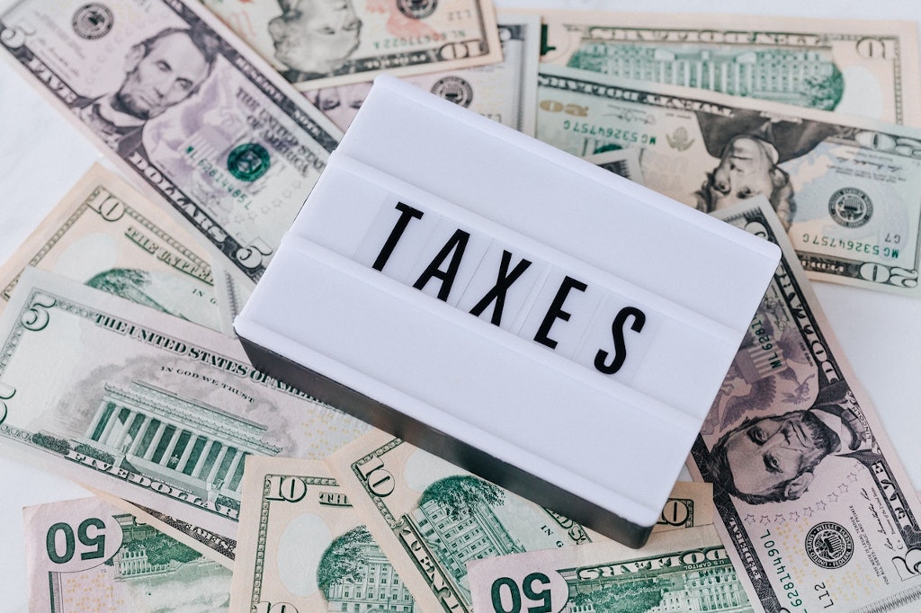 Le mot Taxes écrit sur un fond de billets de 50 dollars américains